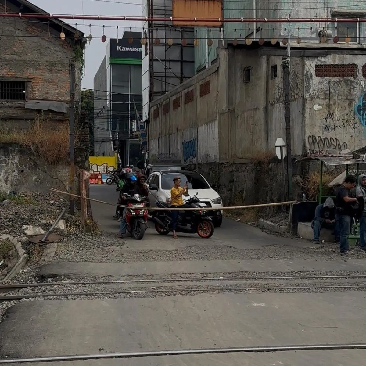 Foto: Perlintasan lokasi taksi tertemper KRL di Bekasi Timur hanya ditutup palang bambu. Perlintasan tak resmi tersebut dijaga warga secara bergantian. (Isal M/detikcom)