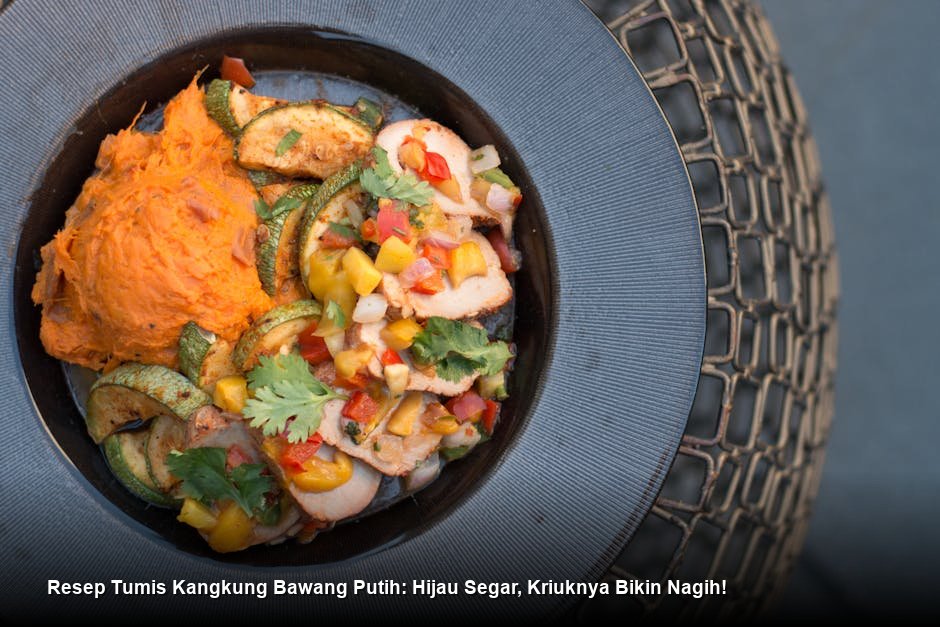 Tumis kangkung bawang putih yang baru diangkat dari wajan, terlihat sangat hijau cerah, mengkilap, dan ditaburi irisan cabai merah sebagai garnish.