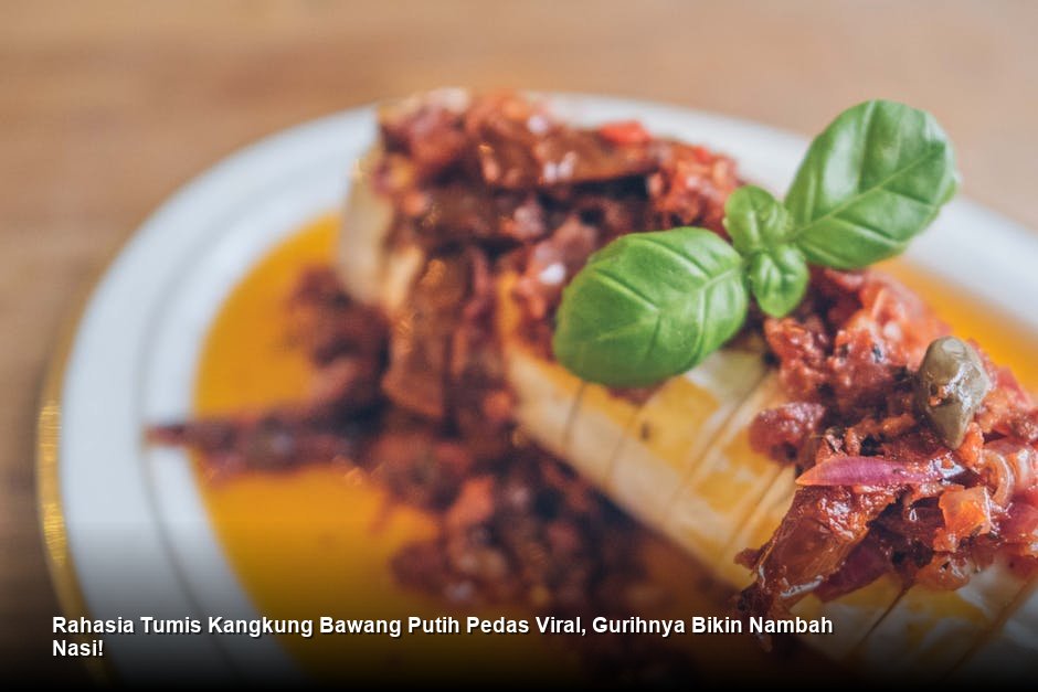 Semangkuk penuh Tumis Kangkung Bawang Putih pedas yang mengkilap, ditaburi irisan cabai merah segar sebagai garnish.