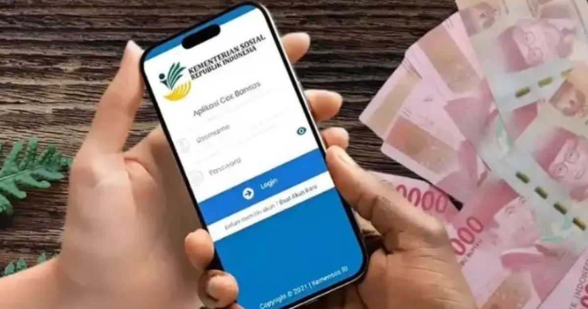 Seorang warga menunjukkan Kartu Keluarga Sejahtera di depan mesin ATM Bank Penyalur untuk melakukan pengecekan saldo bantuan sosial secara mandiri.