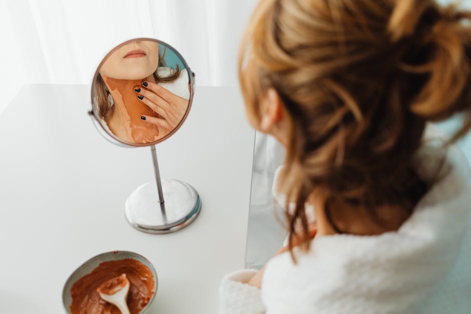 Seorang wanita sedang mengoleskan krim tabir surya di wajahnya sebagai bagian dari rutinitas perawatan kulit pagi hari di bawah sinar matahari.