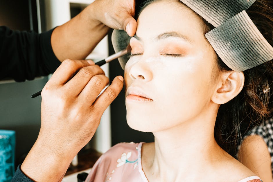 Seorang wanita tersenyum sambil mengaplikasikan serum atau pelembap ke wajahnya sebagai bagian dari rutinitas perawatan kulit pagi hari.